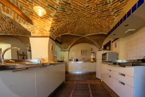 a large kitchen with white cabinets and a brick ceiling at VILLA BOTTERA - Jacuzzi & Private Garden in Riforano +40 photos
