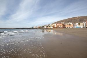 uma praia com edifícios e o oceano e as ondas em Estudio Erbania em Gran Tarajal