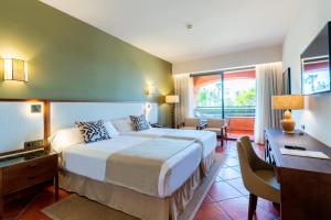 a hotel room with a large bed and a desk at Puerto Antilla Grand Hotel in Islantilla