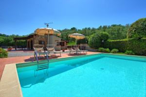 einen Pool mit Stühlen und Sonnenschirmen neben einem Haus in der Unterkunft Cuccardino by PosarelliVillas in Bibbona