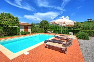 einen Pool mit einem Sonnenschirm, 2 Stühlen, einem Tisch und einem Sonnenschirm in der Unterkunft Cuccardino by PosarelliVillas in Bibbona