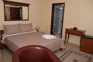 1 dormitorio con cama, mesa y espejo en Hotel Tivoli en Tetovo