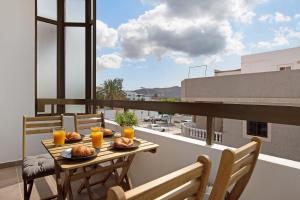 un balcón con una mesa con comida y zumo de naranja en Erbania 2, en Gran Tarajal