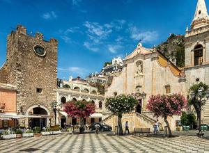 a large building with a clock tower in a city at Casa Amelia - Charme in Taormina in Taormina