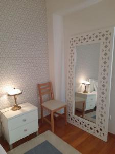 a bedroom with a mirror and a chair and a table at Casa da Ria Barra, Free garage in Gafanha da Nazaré
