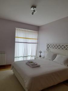 a bedroom with a large white bed with a window at Casa da Ria Barra, Free garage in Gafanha da Nazaré