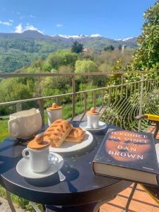 a table with a book and cups of coffee and bread at Villa Magnolia Oliveti in Crosano