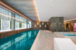 een zwembad in een hotelkamer met een bad en ramen bij Sumus Hotel Monteplaya & SPA 4Sup - Adults Only in Malgrat de Mar