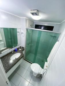 a bathroom with a shower and a toilet and a sink at Acomodação aconchegante à beira- mar in Natal