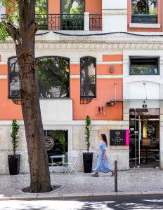una mujer caminando por una calle en frente de un edificio en Hotel Luena en Lisboa