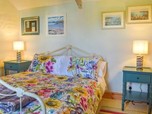 a bedroom with a bed with a colorful comforter and two lamps at Puffin Cottage in Abereiddy