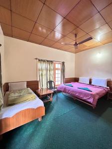 a bedroom with two beds and a table and a window at Zambala guest house in Deskit