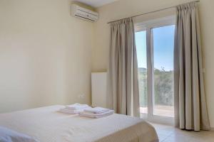 a bedroom with a bed and a large window at Poulades Villa, Corfu in Danilia