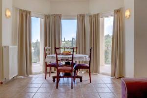 a dining room with a table and chairs and windows at Poulades Villa, Corfu in Danilia