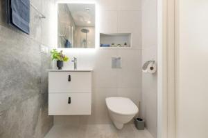 een witte badkamer met een toilet en een wastafel bij Kalevi City Center Apartment in Tartu