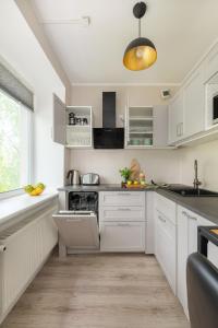 een witte keuken met witte kasten en een raam bij Kalevi City Center Apartment in Tartu