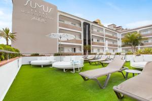 an outdoor patio with white chairs and tables and grass at Sumus Hotel Monteplaya & SPA 4Sup - Adults Only in Malgrat de Mar
