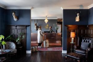 a man standing at a reception desk in a blue room at The Falcon Hotel in Allinge