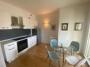 a kitchen with white cabinets and blue chairs and a table at Grande monolocale con parcheggio interrato incluso in Genova