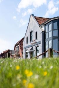 a gray building with yellow flowers in the grass at Nordseehotel Tausendschön in Carolinensiel