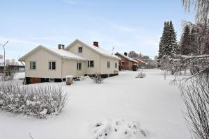 a house is covered in snow in a yard at Old Post Office now cosy apartment close to nature in Hedenäset