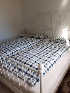 a white bed with a blue and white checkered blanket at Old Post Office now cosy apartment close to nature in Hedenäset