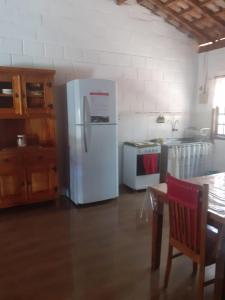 a kitchen with a white refrigerator and a table at CHACARA ENCANTO DO VALE in Mairinque