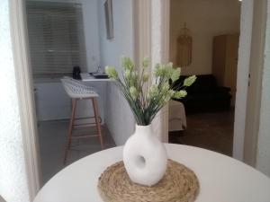 a white vase with flowers sitting on a table at President Guest House in Keratokampos