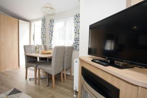 a living room with a table and a flat screen tv at Luxury holiday retreat set within Oakdene Forest - Park activities pass included free! in Saint Leonards