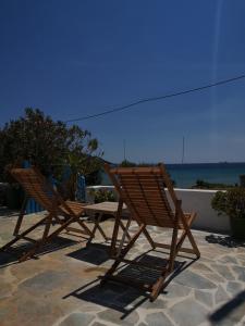 dos sillas de madera sentadas junto a una mesa y el océano en Asimina's beach house, en Ándros