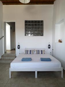 Cama en habitación con pared blanca en Asimina's beach house, en Ándros