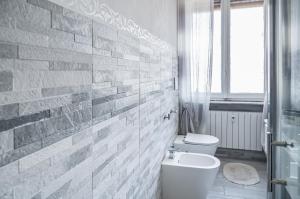 baño con aseo blanco y pared de ladrillo en Selly House Allesandria, en Alessandria
