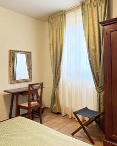 a bedroom with a bed and a desk and a window at Biagetti Bedrooms Affittacamere in Santa Maria degli Angeli