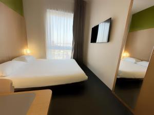 Habitación pequeña con 2 camas y espejo. en B&B HOTEL Metz Est Technopole Pôle Santé en Ars-Laquenexy