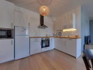 eine große Küche mit weißen Geräten und Holzböden in der Unterkunft La Bourboule Centre - Magnifique T3 avec Balcon, Wi-Fi, Animaux Acceptés - FR-1-608-119 in La Bourboule + 4 Fotos