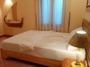 Un dormitorio con una cama blanca con una mesa y una lámpara en Vaali Maldives Island Escapes & Dive, en Felidhoo
