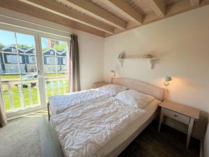 ein Schlafzimmer mit einem Bett und einem großen Fenster in der Unterkunft Strandpark Sierksdorf H054 in Sierksdorf