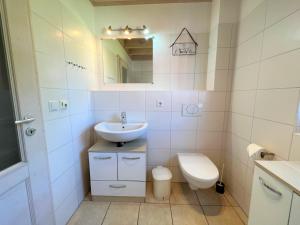 ein Badezimmer mit einem Waschbecken, einem WC und einem Spiegel in der Unterkunft Strandpark Sierksdorf H054 in Sierksdorf