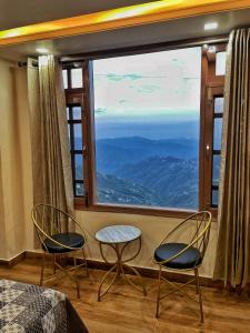 two chairs and a table in front of a large window at Aammk homes in Shimla