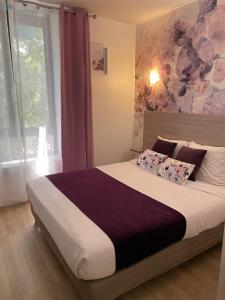 a bedroom with a large bed with a large window at Empire Hôtel in Nîmes
