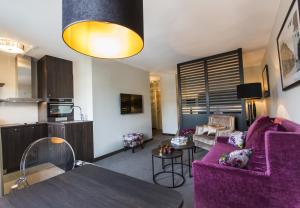 a living room with a purple couch and a kitchen at Saga Apartments Oslo in Oslo