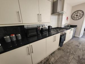 a kitchen with white cabinets and a black counter top at Impeccable 2-Bed Apartment in Birmingham in Birmingham