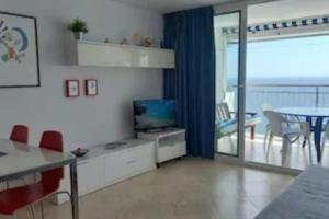 sala de estar con TV y mesa con sillas en Ely Palace, vistas al mar/4pax en Platja  d'Aro