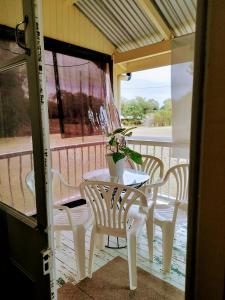 a table and chairs on a porch with a potted plant at Home at the beach in Ingham in Allingham