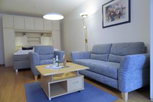 - un salon avec un canapé bleu et une table dans l'établissement Haus Seerose App 2 inkl WLAN, à Grömitz
