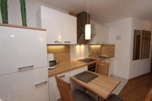 une cuisine avec des placards blancs et une table en bois dans l'établissement Haus Seerose App 2 inkl WLAN, à Grömitz