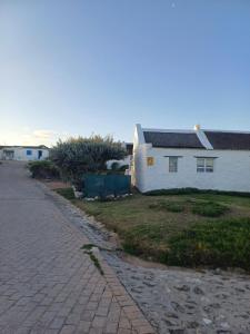 une route de briques à côté d'une maison blanche dans l'établissement Kassiesbaai Cottage, à Arniston