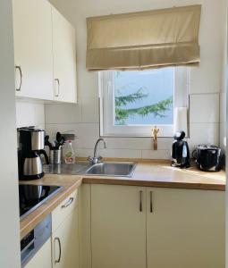 uma cozinha com armários brancos, um lavatório e uma janela em Beach inkl WLAN em Grömitz