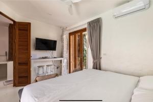- une chambre avec un lit blanc et une télévision dans l'établissement lory‘s home, à Bangkok