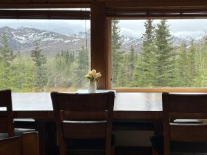 a dining room table with chairs and a large window at Denali Park View House in Healy